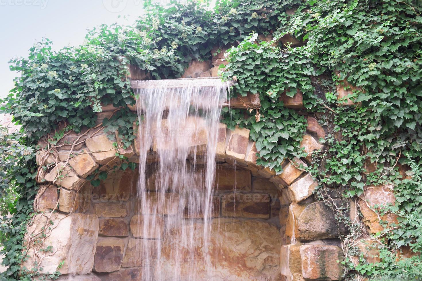 Wasserfall fließt und lebendige Pflanzendekoration im gemütlichen Stadtpark foto