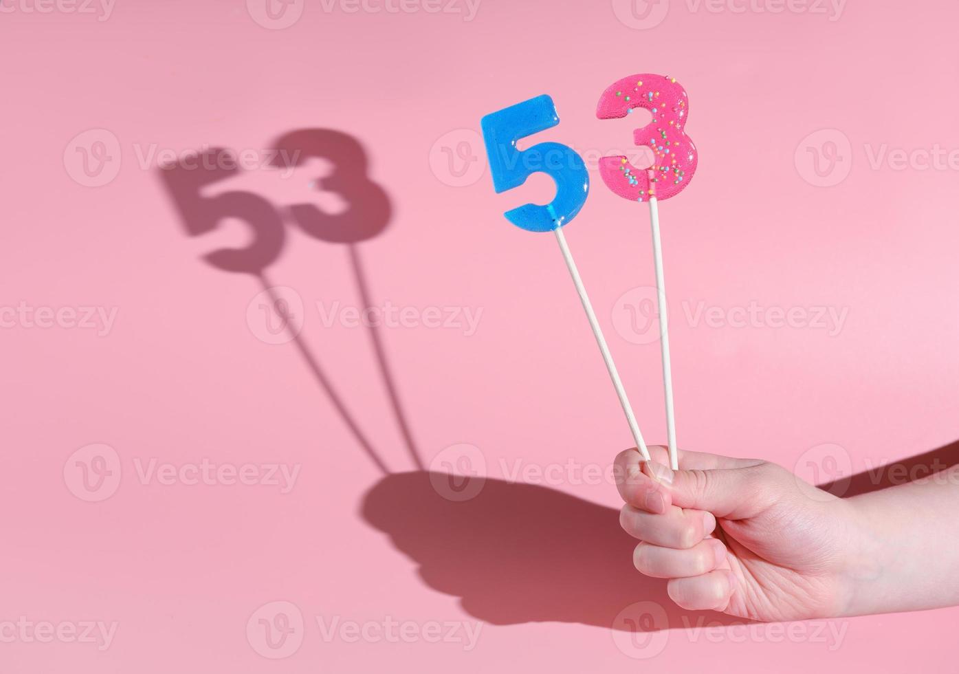 die Hand des Mädchens, die einen 5 und 3 geformten Lolipop hält. foto