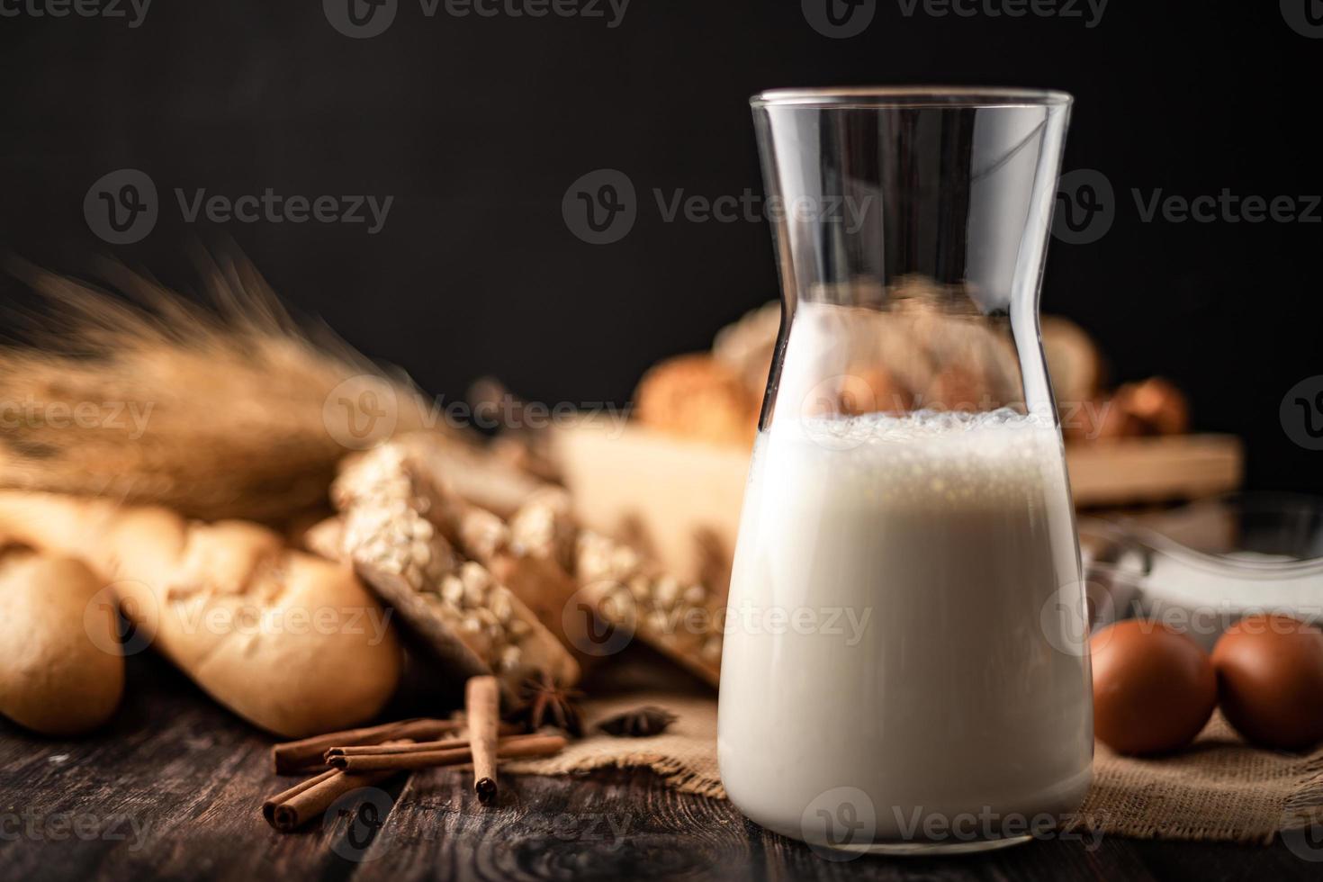 Milch in einer Glasflasche auf einem Holztisch mit Zutaten foto