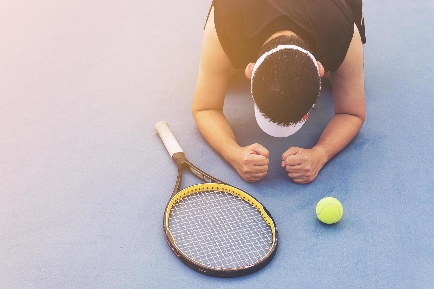 Trauriger Tennisspieler, der auf dem Platz sitzt, nachdem er ein Match verloren hat foto