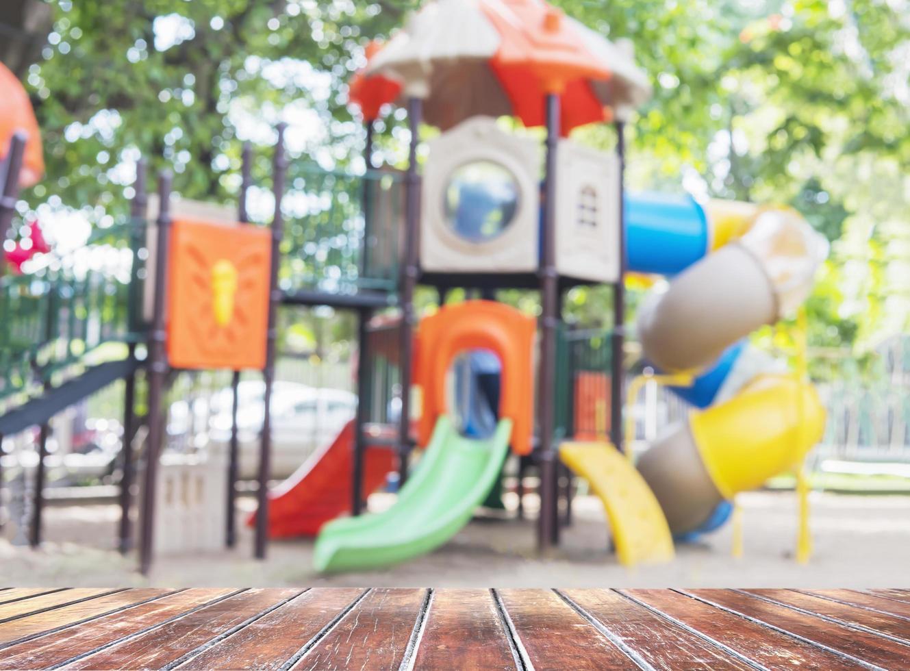 brauner holzboden über unscharfem spielplatzpark foto