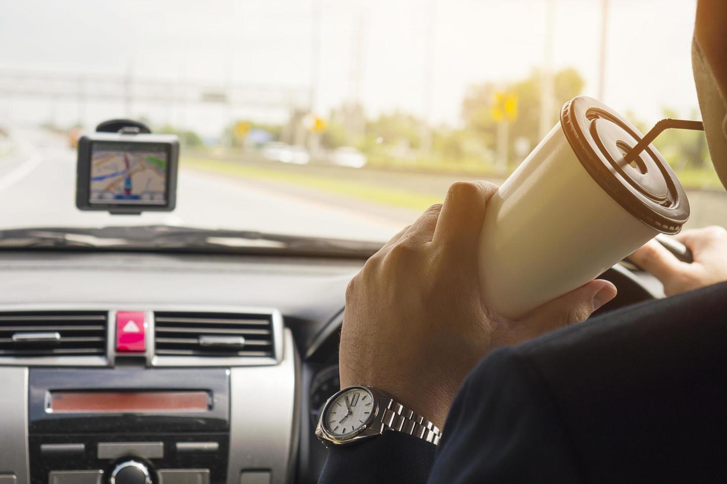 Mann fährt Auto mit Navigator und trinkt Kaffeetasse foto