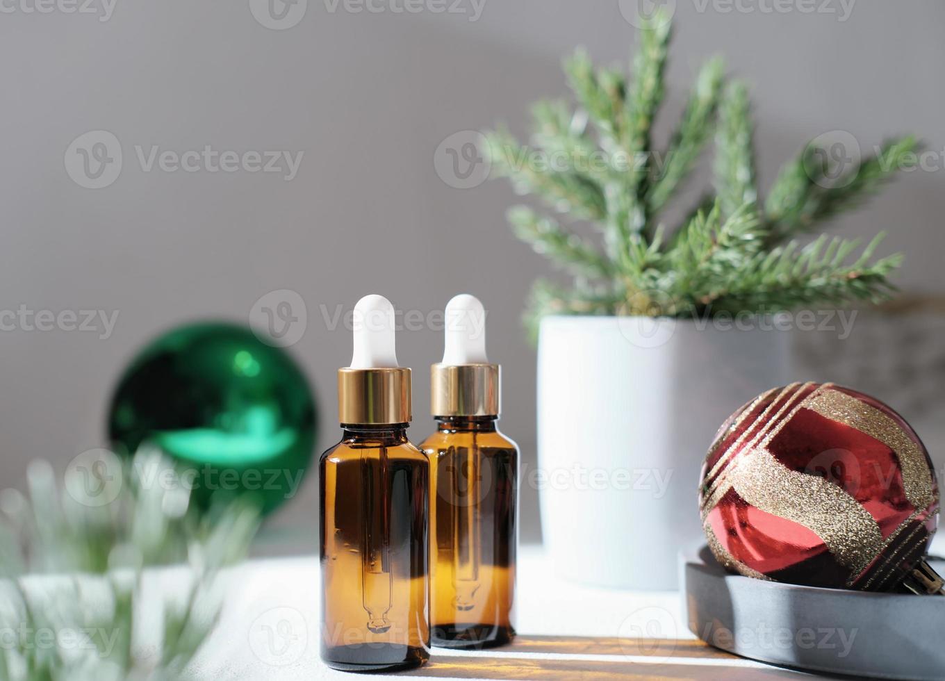 Zwei braune Glasflaschen mit Tropfpipetten auf einem Tisch mit Weihnachtsdekor. Serum-Öl für Haarhasen und Wachstum, Feiertagsverkauf und Werbung. Weihnachtskugeln und Tannenzweige foto