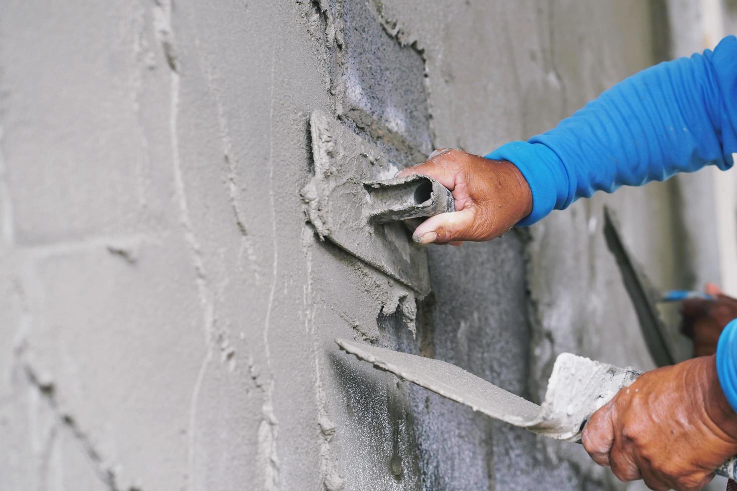 hand des arbeiters, der zement an der wand verputzt foto