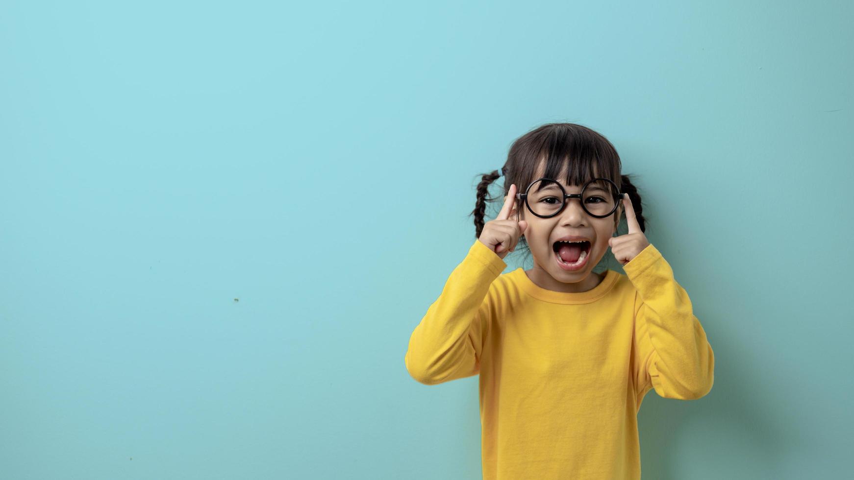 glückliches Kindermädchen mit Brille für das Sehvermögen hat eine modische Frisur auf hellgrünem Hintergrund. foto