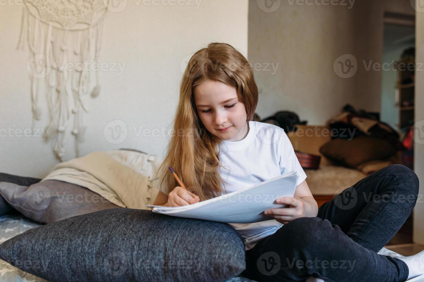 das mädchen nach der schule spielt zu hause, zeichnet mit bleistiften und filzstiften foto