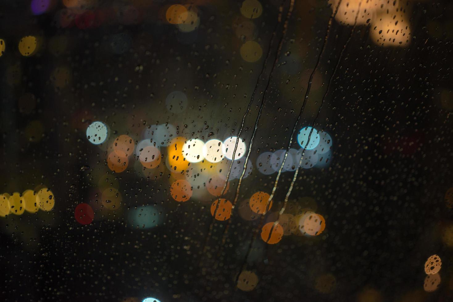 Wassertropfen auf Fenster mit bokeh hellem Hintergrund der nächtlichen Stadtansicht foto