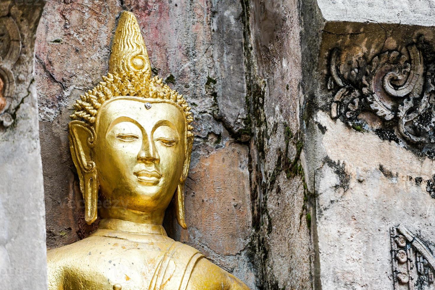 große goldene Buddha-Statue mit alter Hintergrundwand. foto