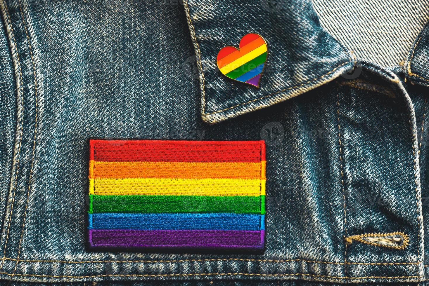 nahaufnahme des lgtbi-flaggen-textilpatches auf einer jeansjacke und lgtbi-nadel in herzform. Pride-Day-Konzept foto