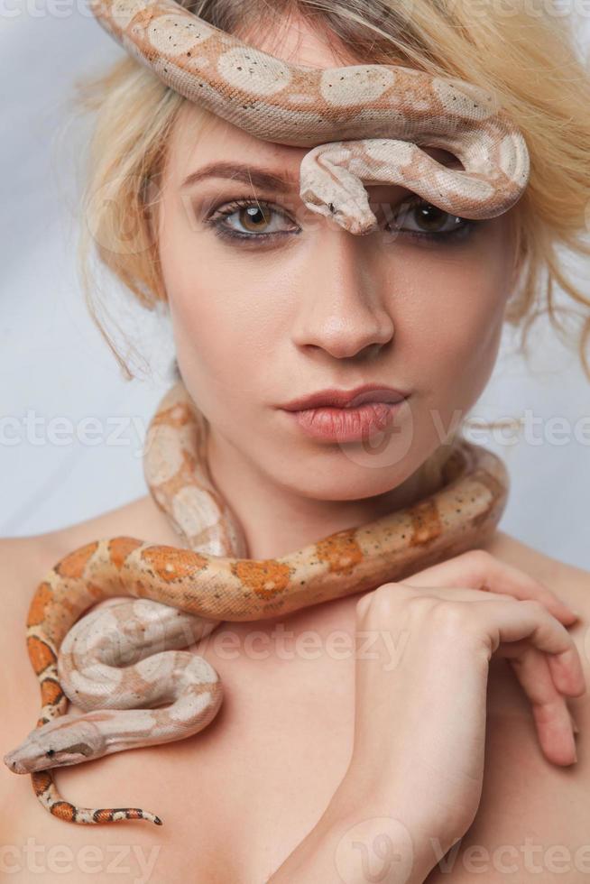schönes Mädchen und die Schlange Boa Constrictors, die sich umhüllt foto