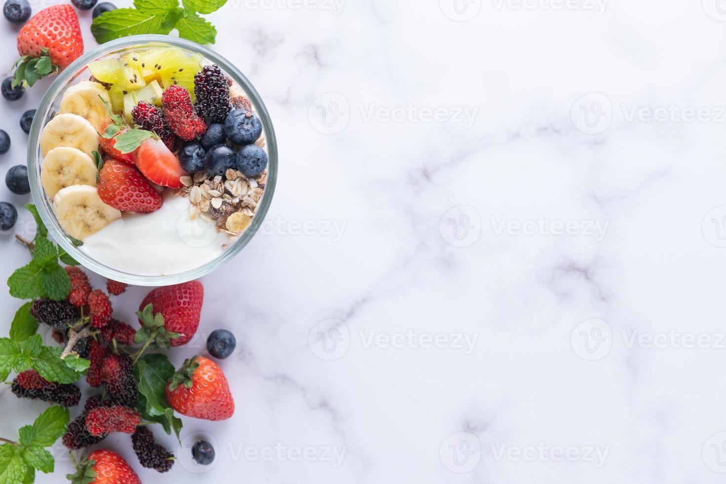 schüssel hafermüsli mit joghurt, frischen blaubeeren, maulbeere, erdbeeren, kiwi, banane, minze und nussbrett für gesundes frühstück, draufsicht, kopierraum, flache lage. vegetarisches Essenskonzept. foto