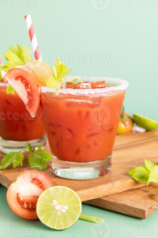 Glas Glas Tomatensaft, Limette mit frischem, hellem Tomatenbündel isoliert auf grünem Hintergrund, grüne Petersilie. Gemüsegetränk. foto