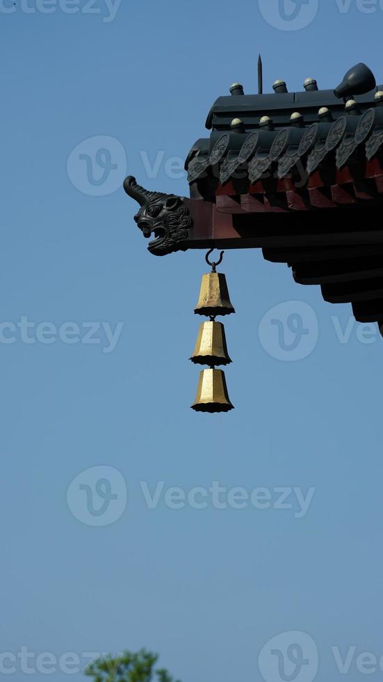 die goldene Glocke, die in einem Tempel des Porzellans an der Spitze der Dachtraufe hängt foto