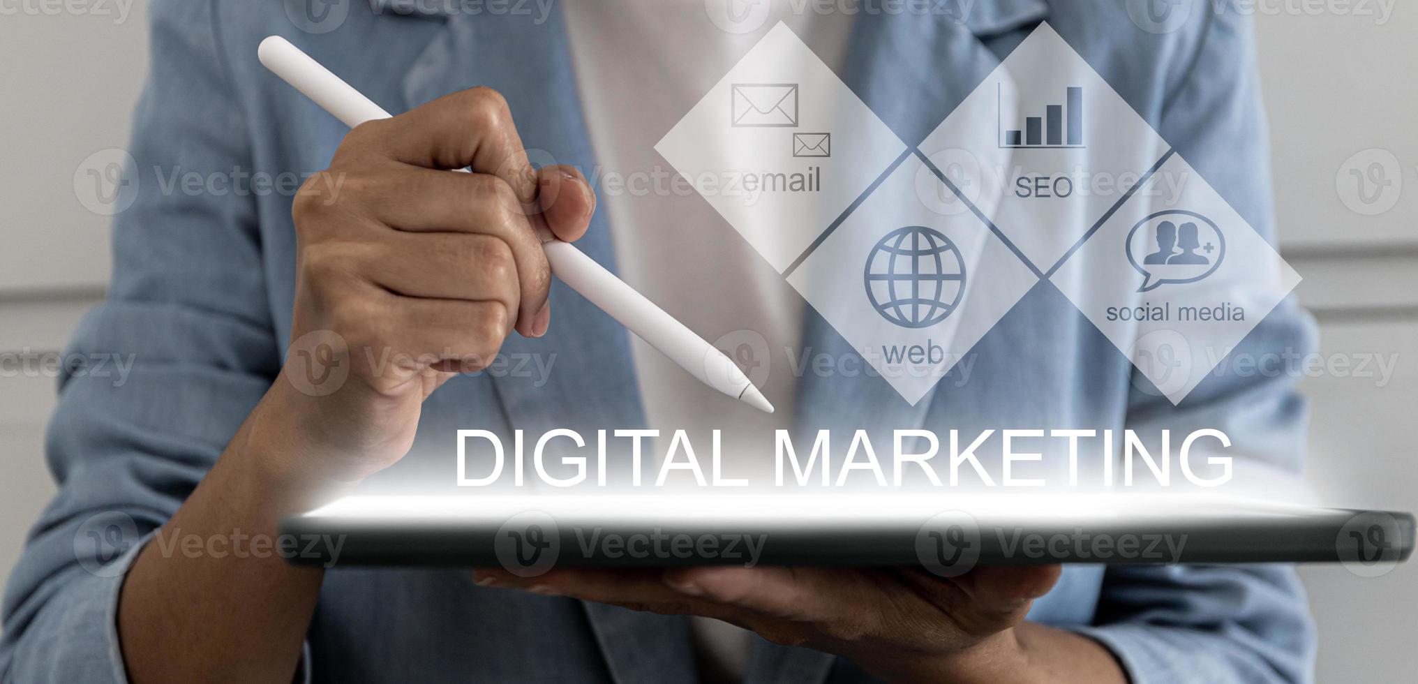 eine Person, die ein Tablett und einen Stift hält und auf einen Bildschirm zeigt, der mit digitalem Marketing gekennzeichnet ist und ein visuelles Symbol für Online-Marketing zeigt. digitales Marketingkonzept. foto