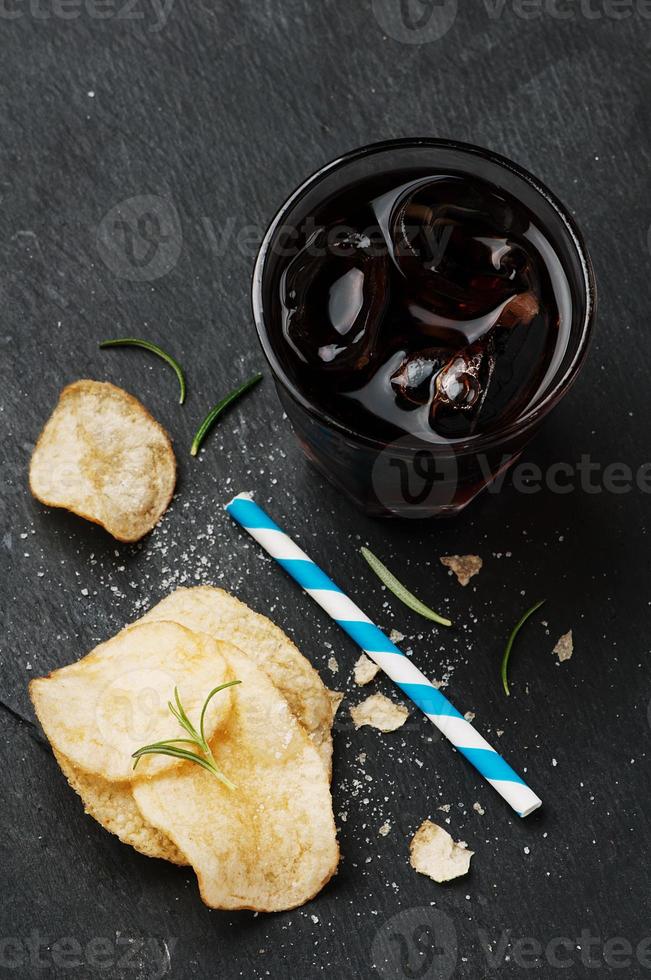 Kartoffelchips und ein Glas Cola auf dem Tisch foto