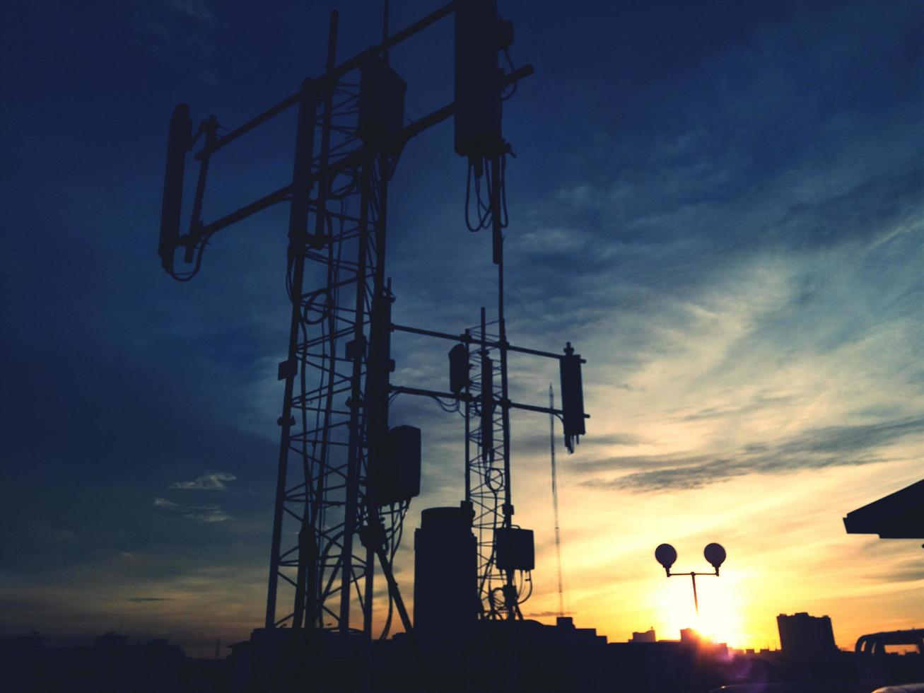 verschwommene Silhouette von Kommunikation, digitalem Fernsehen oder Sendeturm mit Sonnenuntergang, Wolken- und Himmelshintergrund zur Dämmerungszeit. technologie und schönheit im naturkonzept foto