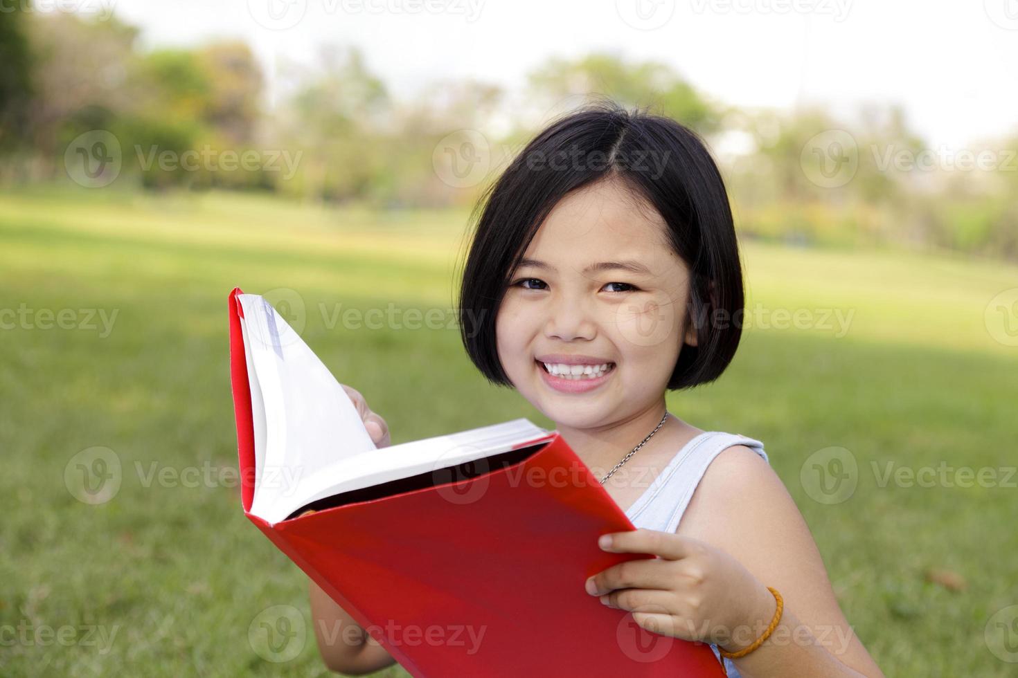 Asiatisches kleines Mädchen liest Buch im Park foto