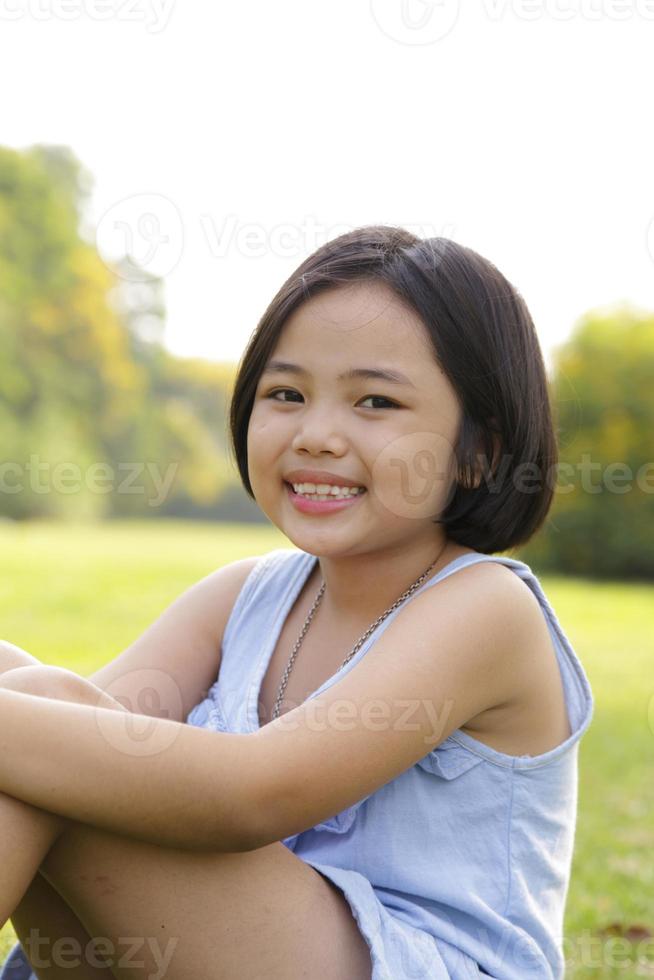 Asiatisches kleines Mädchen, das glücklich im Park lächelt foto