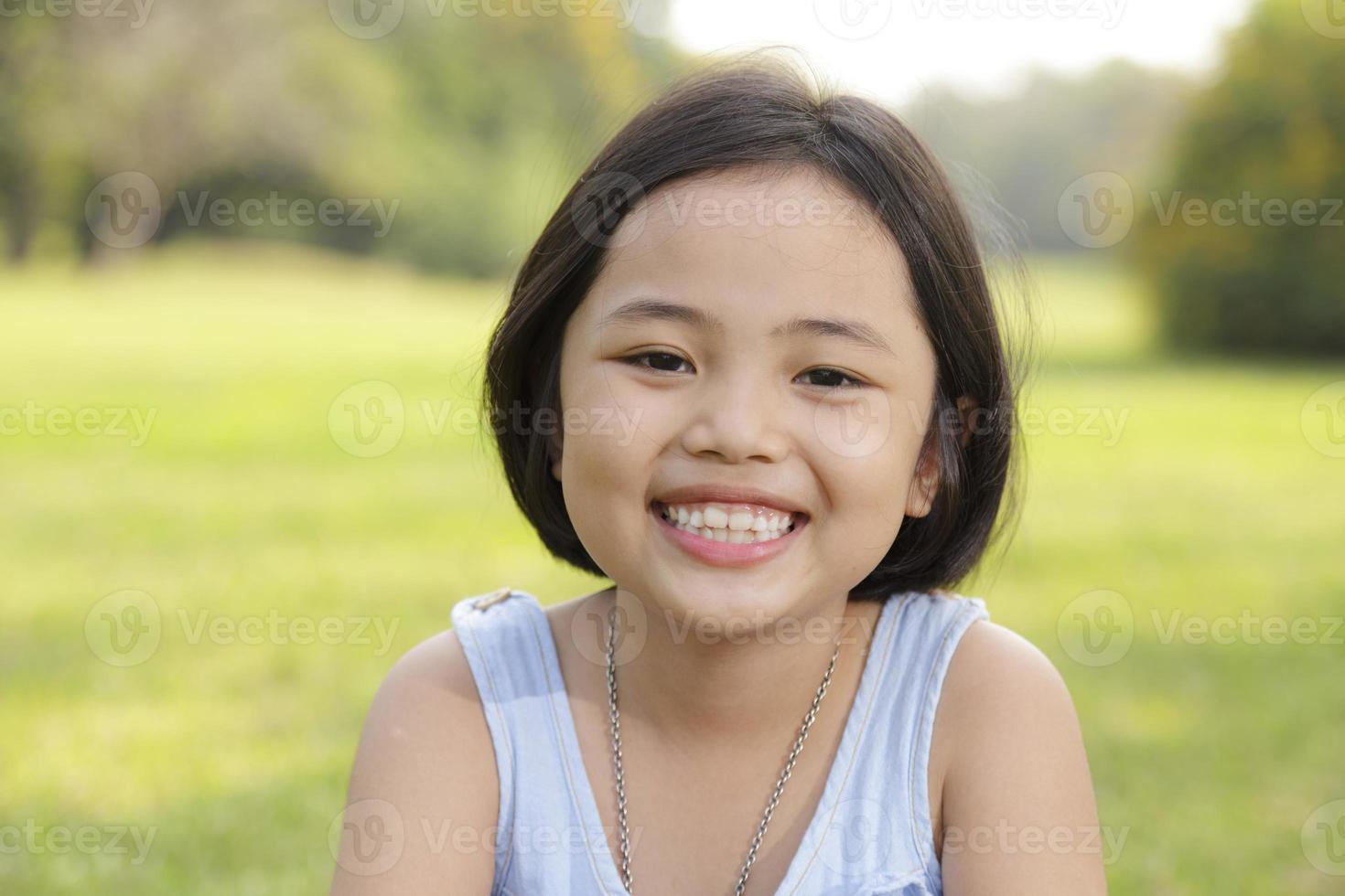 Asiatisches kleines Mädchen, das glücklich im Park lächelt foto