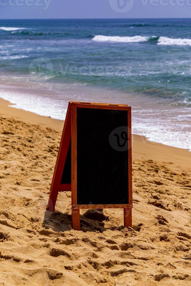 kreidetafel für text, nachricht oder werbung am sonnigen ozeanstrand foto