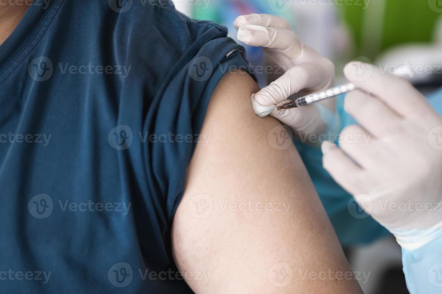 nahaufnahme menschen werden mit einer nadel von medizinischem personal oder krankenschwester oder arzt geimpft. Injektion in den Oberarm. foto