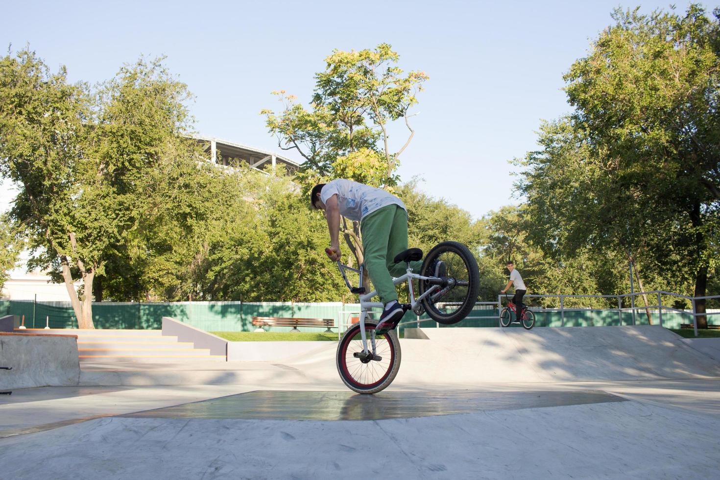 BMX-Fahrertraining und Tricks auf dem Straßenplatz, Fahrrad-Stuntfahrer im cocncrete Skatepark foto