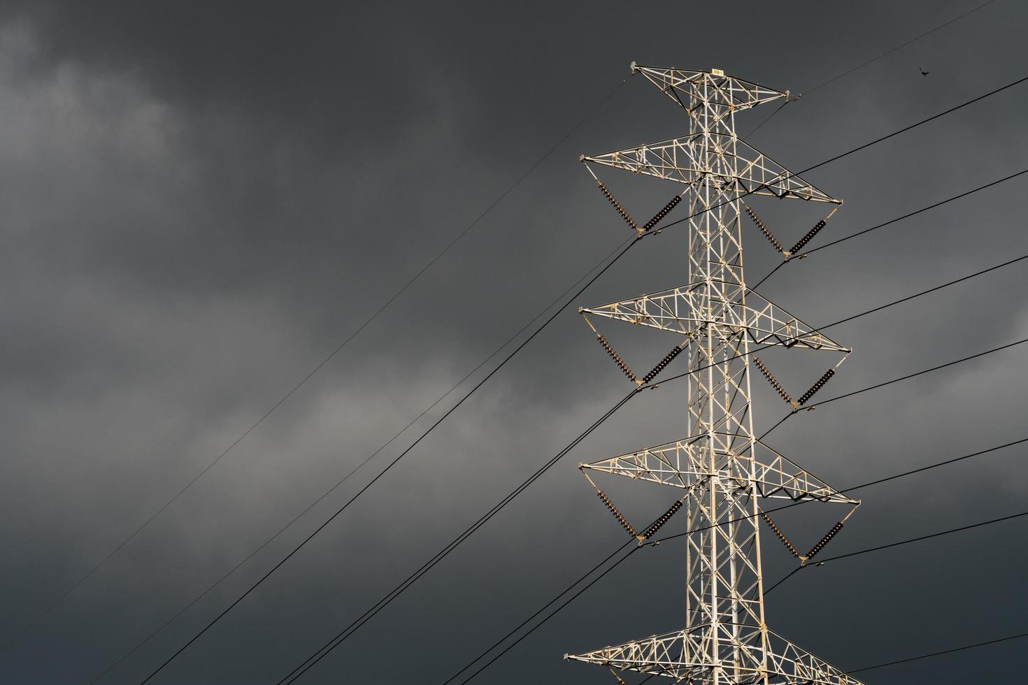 Hochspannungsturm mit Elektrokabel und dunklem Himmel foto