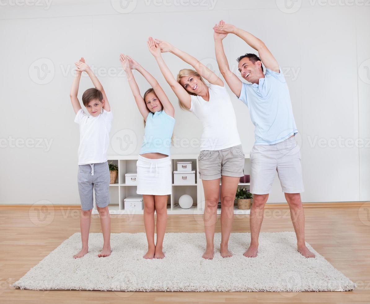 Familie macht Dehnübungen auf dem Teppich foto