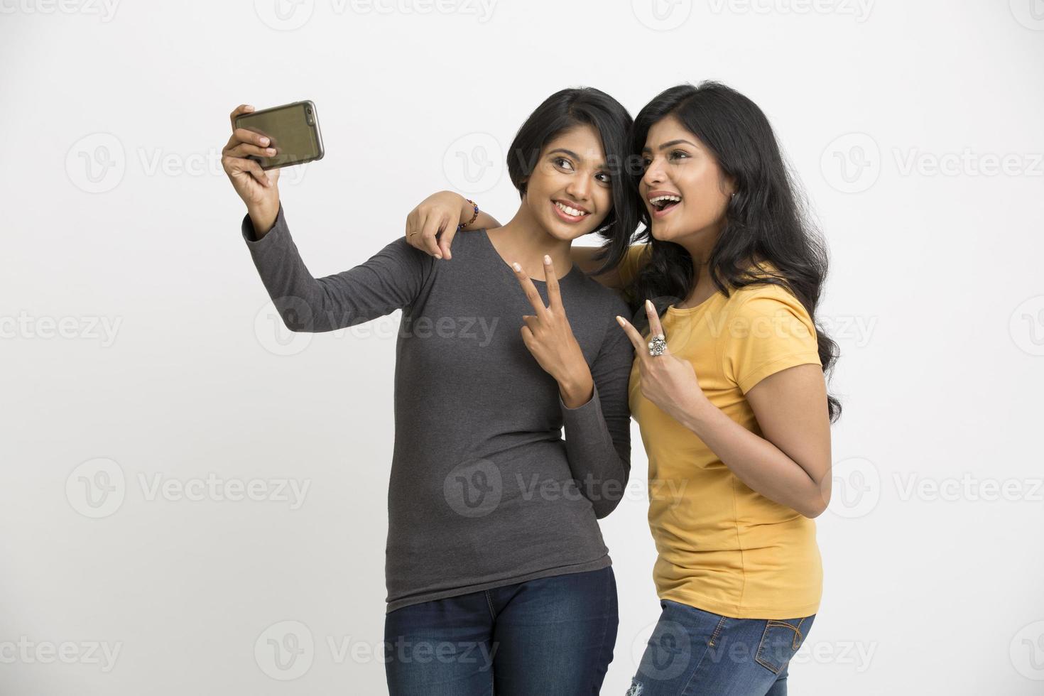 zwei hübsche junge Frauen, die Selfie mit Handy nehmen foto