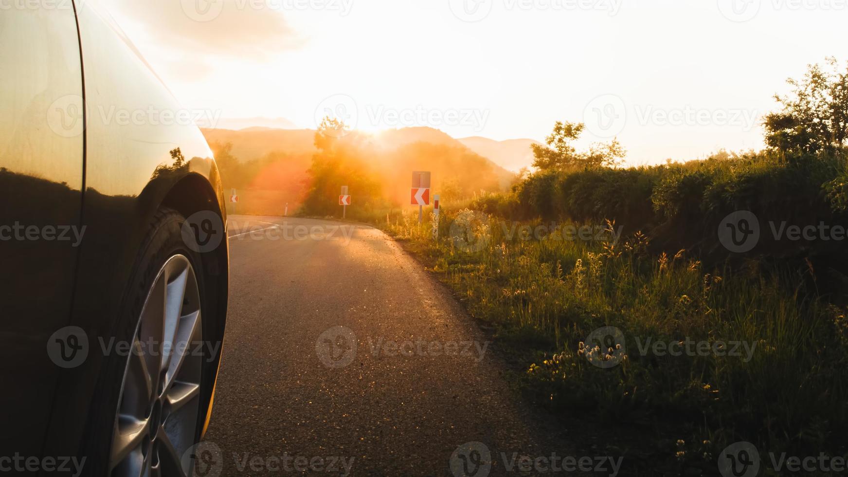 filmischer Low Angle View Reifen auf asphaltierter Straße in Bewegung mit Sonnenuntergang und Rauch im Hintergrund. Roadtrip-Konzept im Freien foto