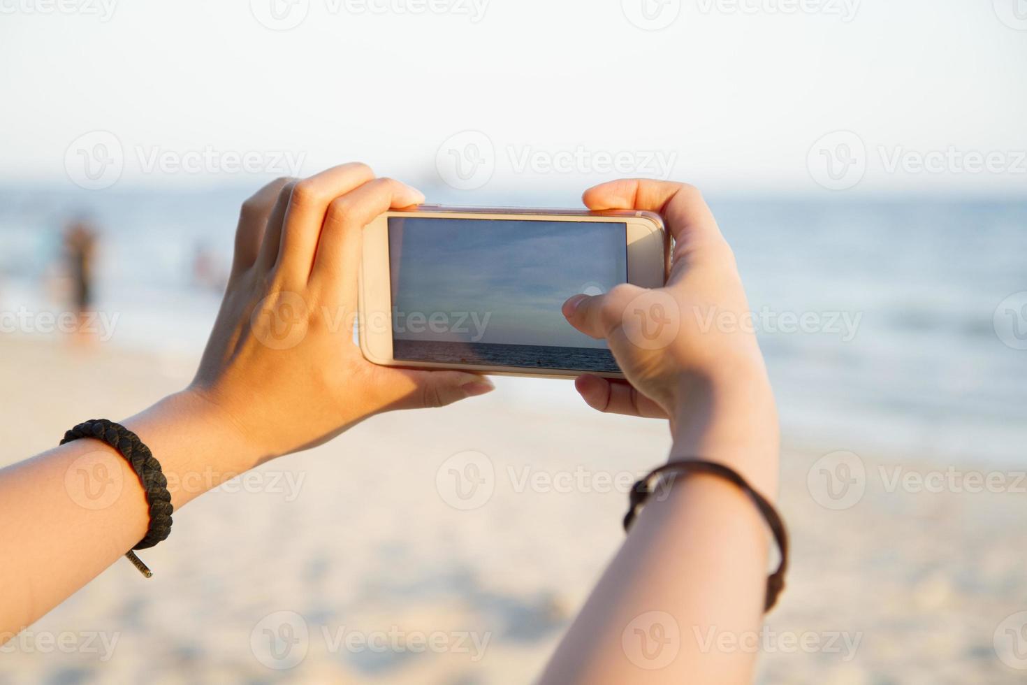 frau, die foto der strandlandschaft mit intelligentem telefon macht