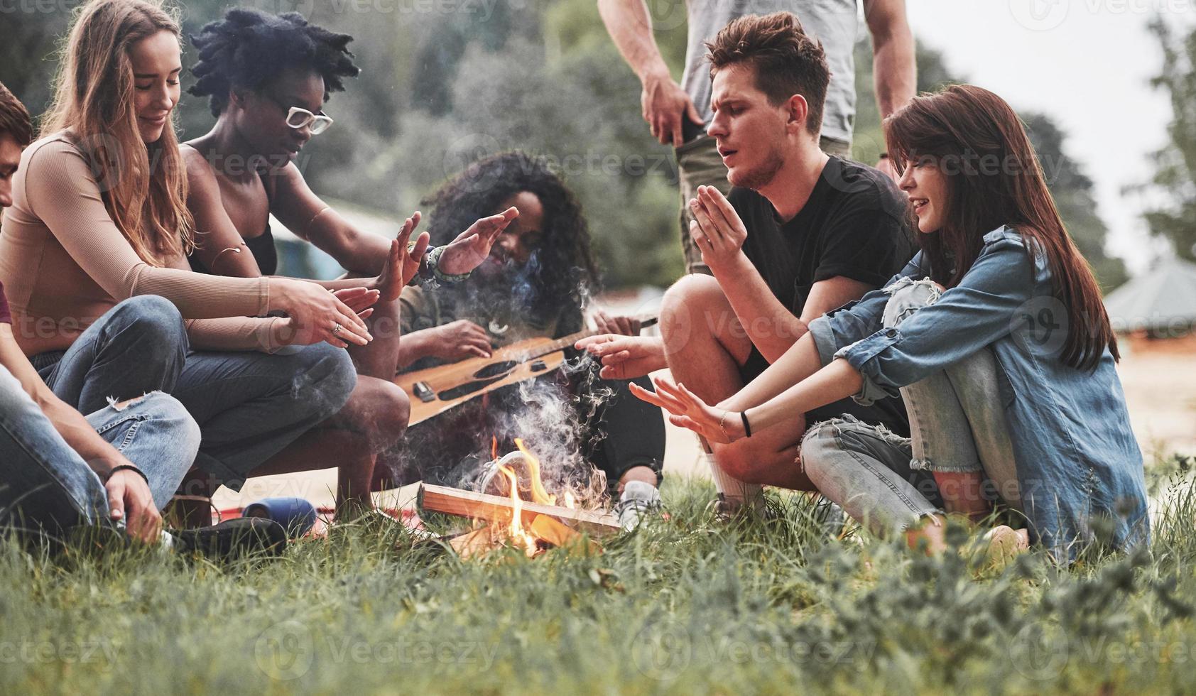 Erwärmung am Lagerfeuer. gruppe von menschen picknickt am strand. Freunde haben Spaß am Wochenende foto