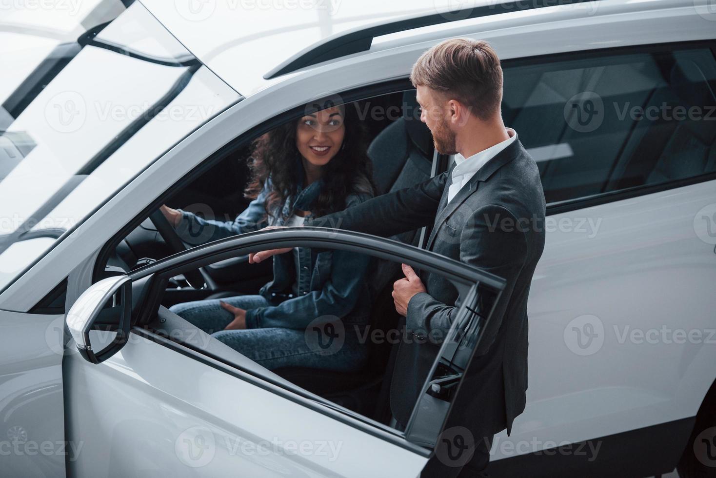 einfach und bequem. Kundin und moderner stylischer bärtiger Geschäftsmann im Autosalon foto