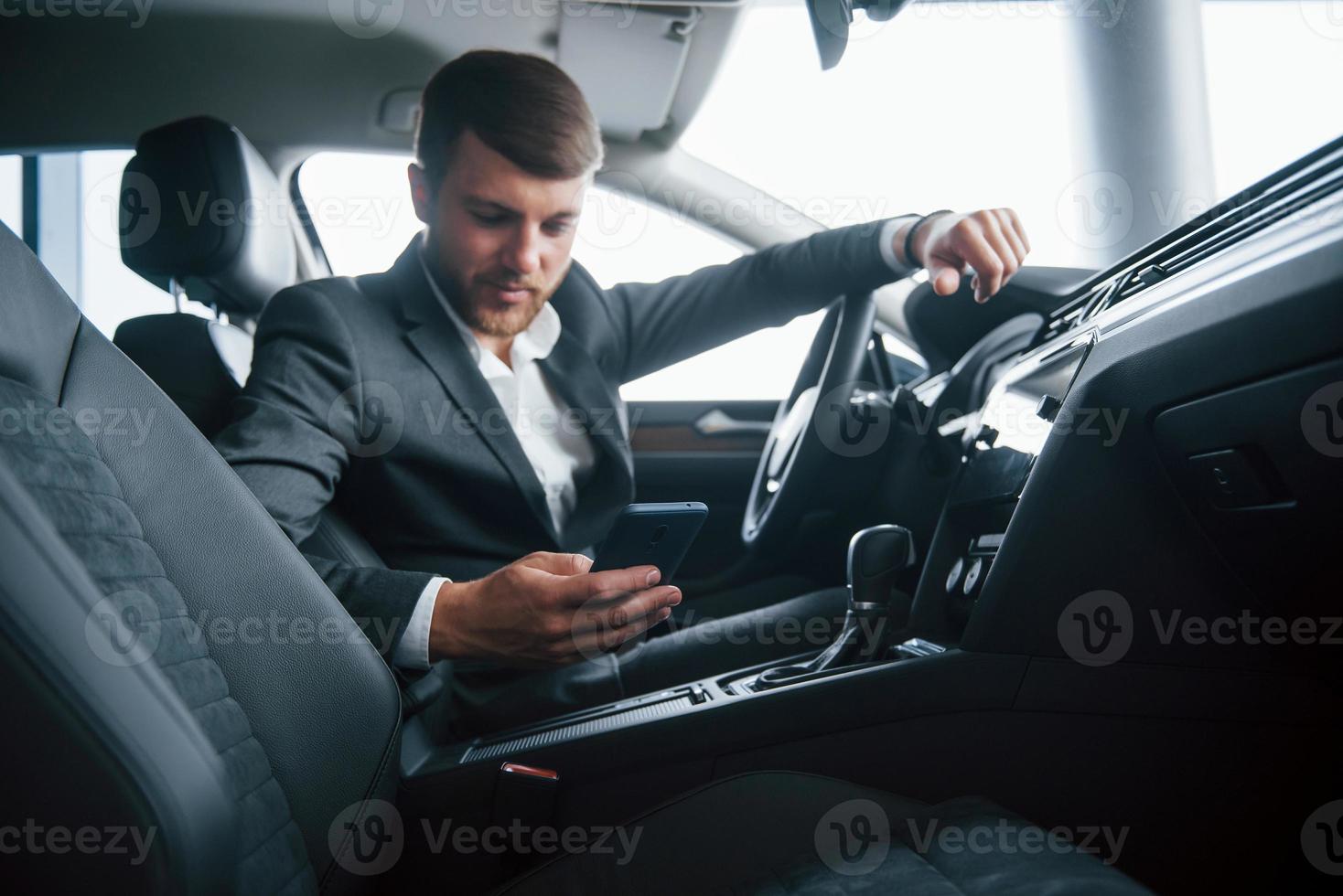 Zeit aufzuhören und eine Pause einzulegen. moderner geschäftsmann, der sein neues auto im autosalon probiert foto