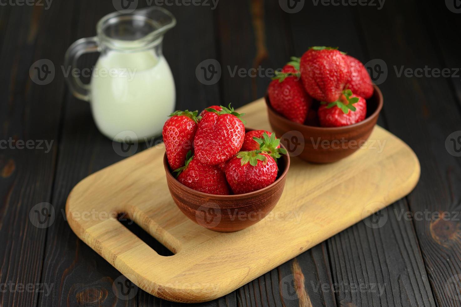 eine schüssel mit roten saftigen erdbeeren auf rustikalem holztisch. gesundes und diät-snack-food-konzept. foto