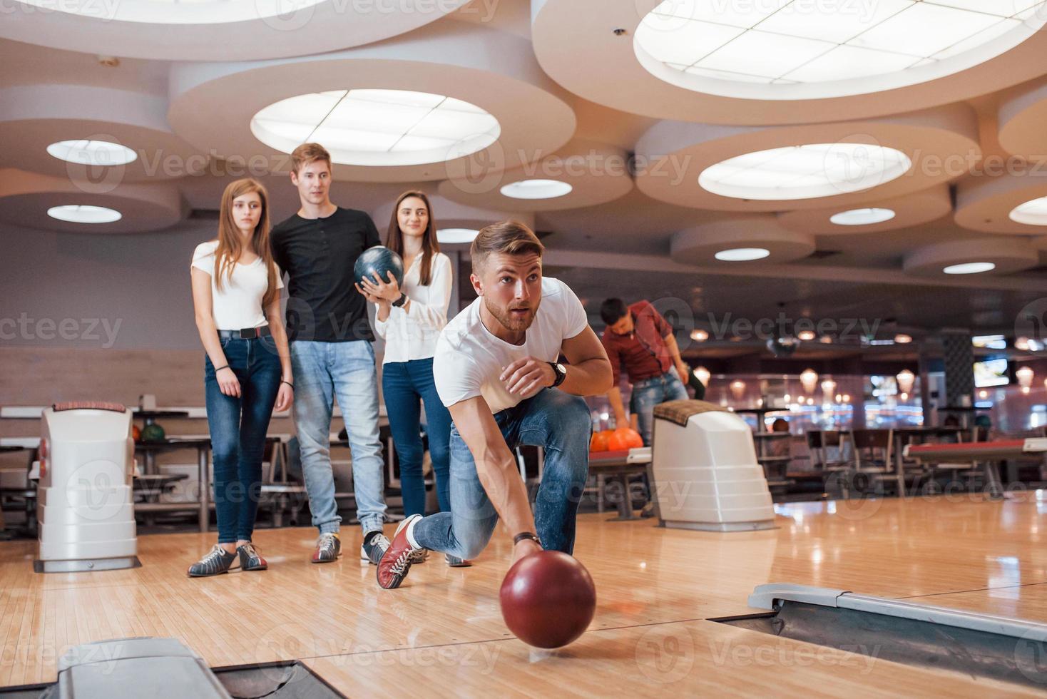 kaukasische Ethnizität. Junge, fröhliche Freunde haben an ihren Wochenenden Spaß im Bowlingclub foto