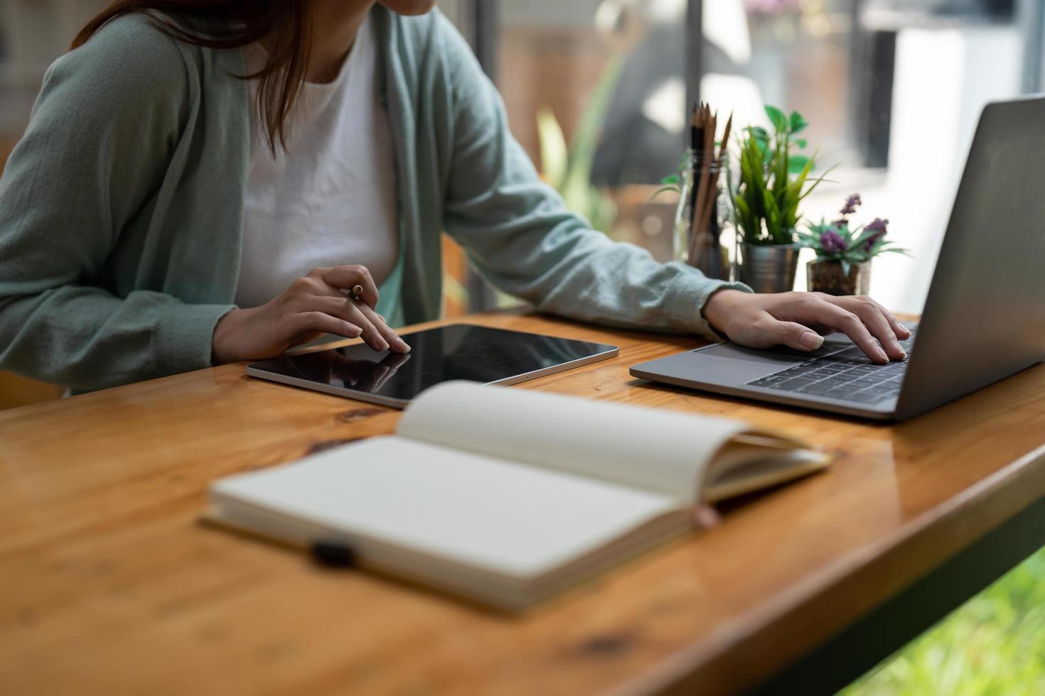 asiatische frau, die schreibt, macht liste, die notizen in notizblock und digitalem tablet macht, die auf laptop zuhause arbeiten oder lernen - bildungskurs oder training, seminar, bildungs-online-konzept foto