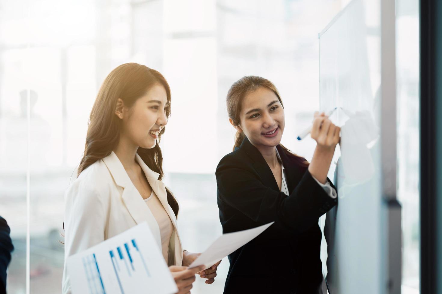 Business Asiatin Präsentation Dirigent Manager Coach Zeichnung Schreibplan auf Whiteboard präsentiert neue Unternehmensstrategie foto