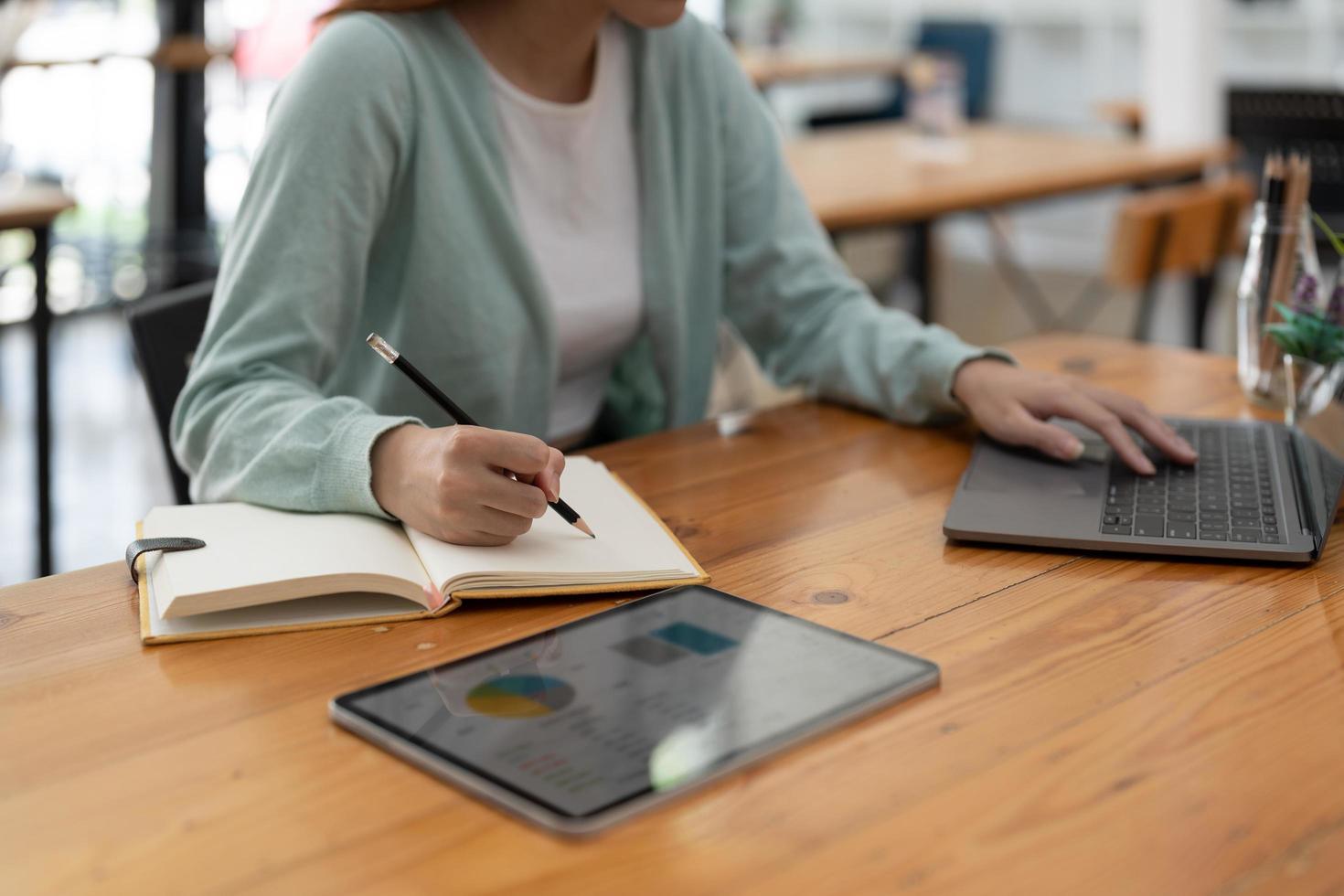 asiatische frau, die schreibt, macht liste, die sich notizen im notizblock macht, der drinnen auf dem laptop arbeitet oder lernt - bildungskurs oder training, seminar, bildungs-online-konzept foto