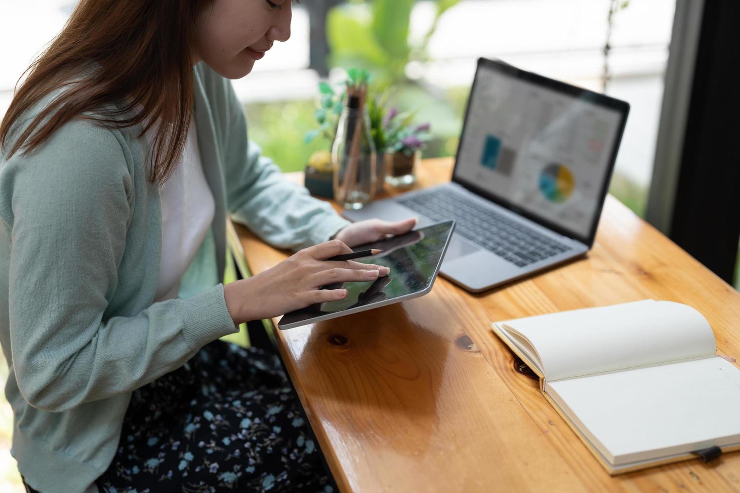 asiatische frau, die schreibt, macht liste, die notizen in notizblock und digitalem tablet macht, die auf laptop zuhause arbeiten oder lernen - bildungskurs oder training, seminar, bildungs-online-konzept foto