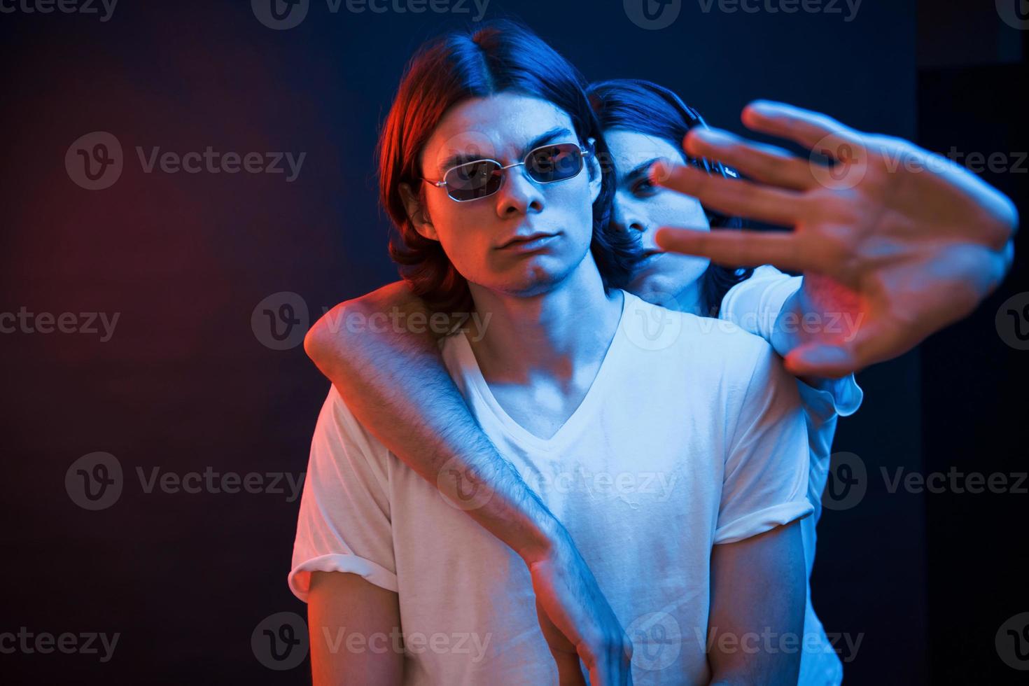 Fass meinen Bruder nicht an. Porträt von Zwillingen. Studioaufnahme im dunklen Studio mit Neonlicht foto