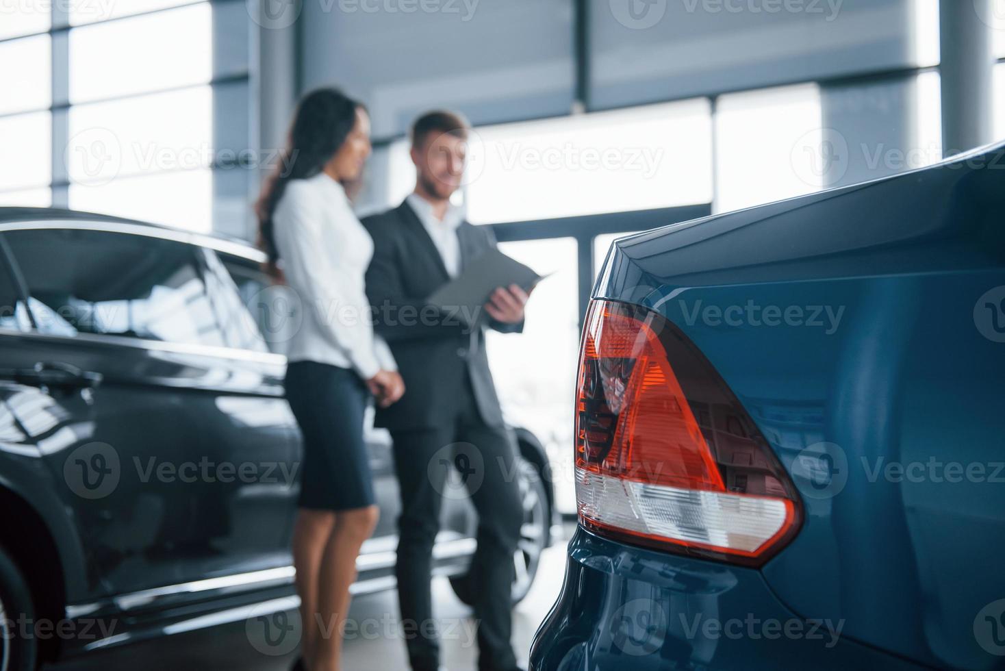 hintere Scheinwerfer. Kundin und moderner stylischer bärtiger Geschäftsmann im Autosalon foto