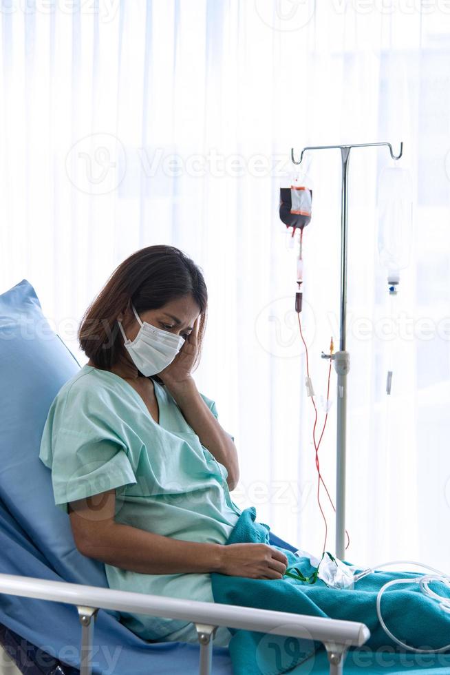 covid-19, ausbruch des corona-virus, quarantäne- und epidemieverbreitungskonzept. asiatische depressive corona- oder covid-19-patienteninfektion tragen eine maske und erhalten eine bluttransfusion im quarantäneraum des krankenhauses foto