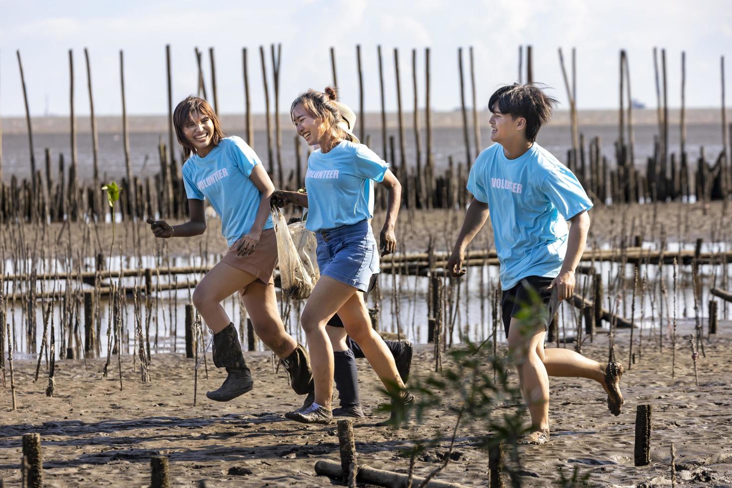 ein team von jungen und vielfältigen freiwilligen arbeitergruppen genießt die karitative sozialarbeit im freien bei der reinigung des müllprojekts im mangrovenwald foto