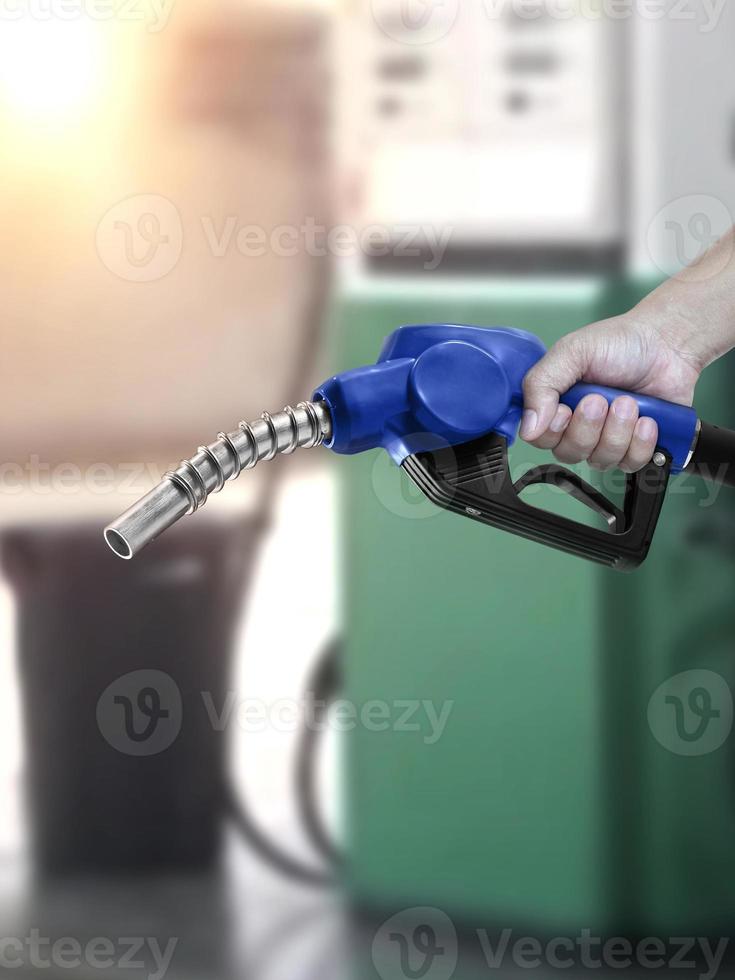 Mann hält Zapfpistole an Tankstelle foto