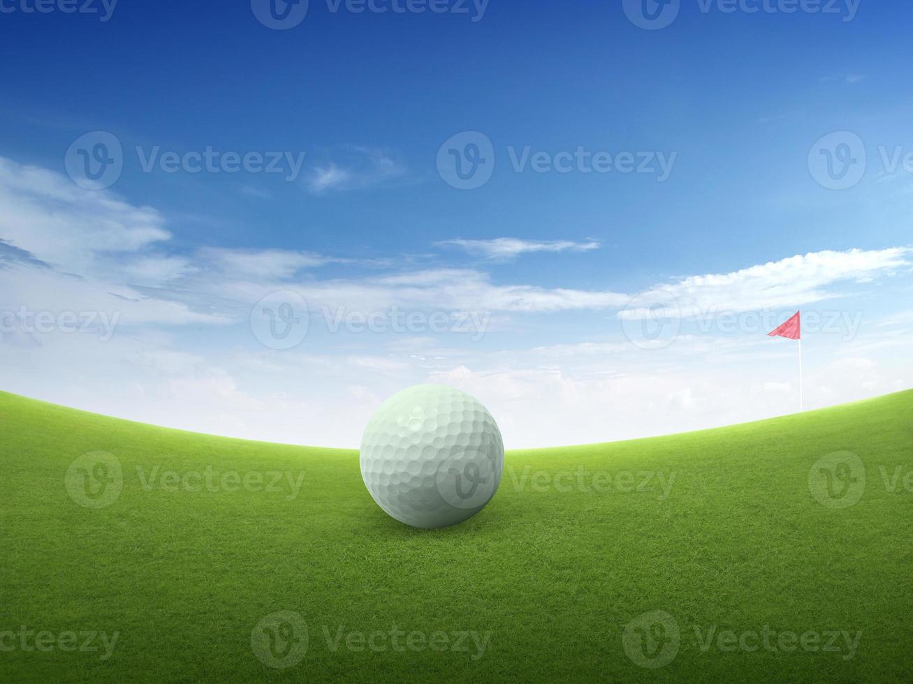 Nahaufnahme des Golfballs auf der grünen Wiese und der roten Golfflagge auf dem grünen Fairway mit schönem blauem Himmel foto