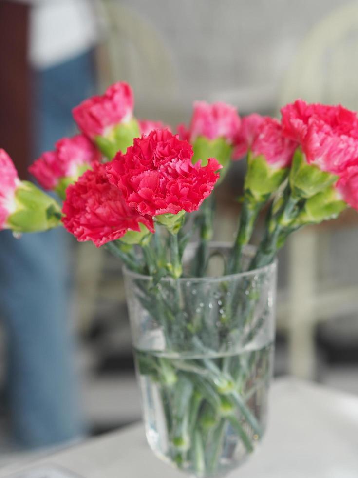 rosa nelkenblume in einem glas wasser auf marmortisch foto