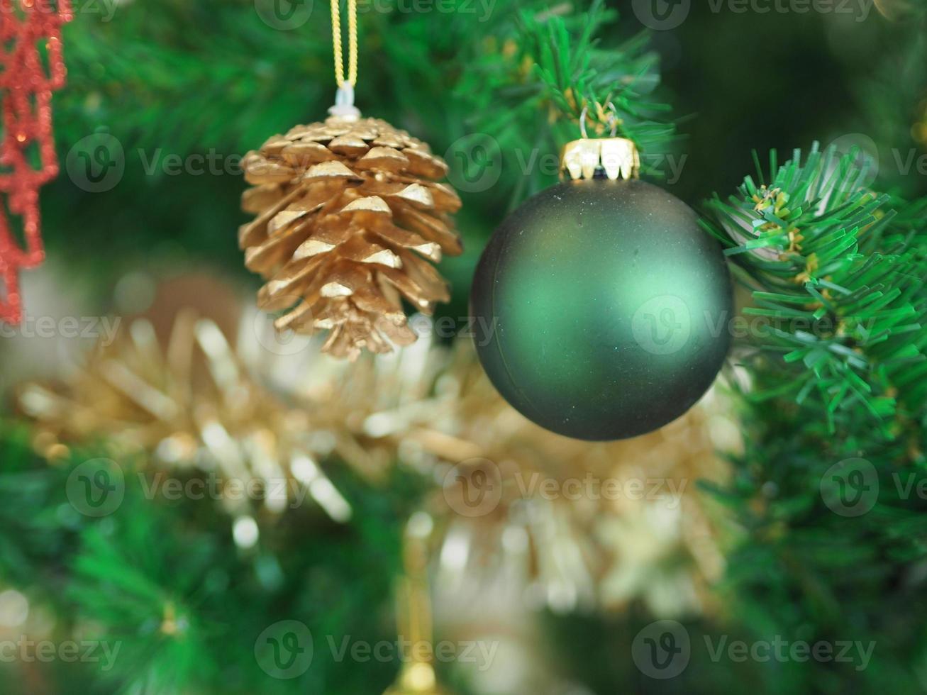 Weihnachtsschmuck grüner Baum hängend, grüne Kugel, goldene Tannenzapfen, umwickelt mit einem goldenen Band auf weißem Hintergrund foto