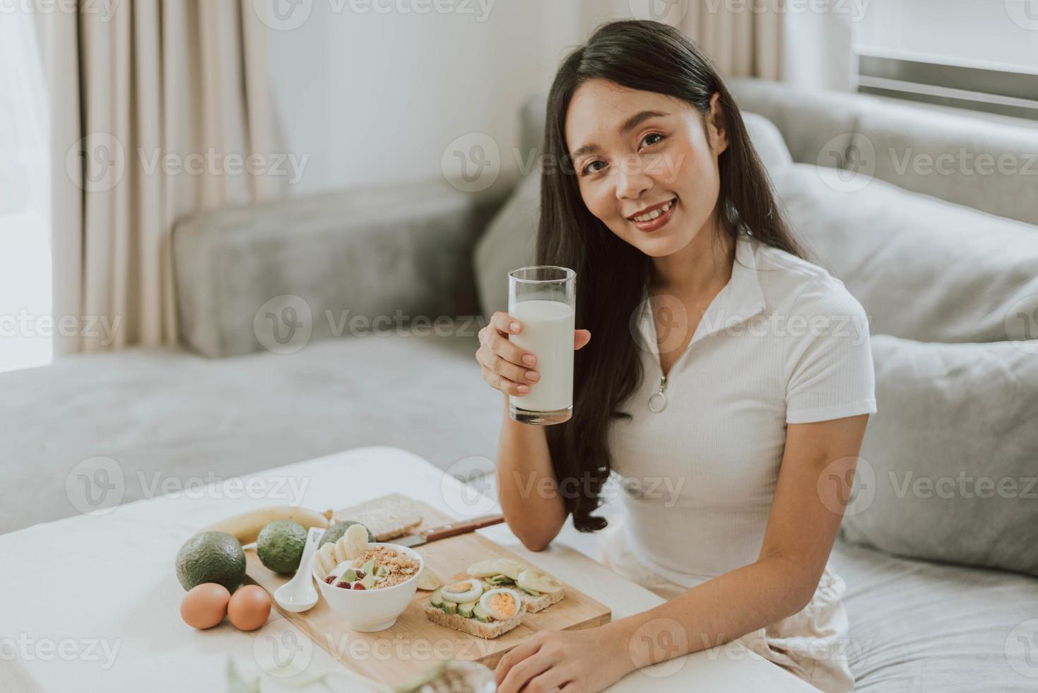 gesunde frau, die milch hält. junge frau, die zu hause gesundes essen kocht. gesundes und wellnesskonzept. foto