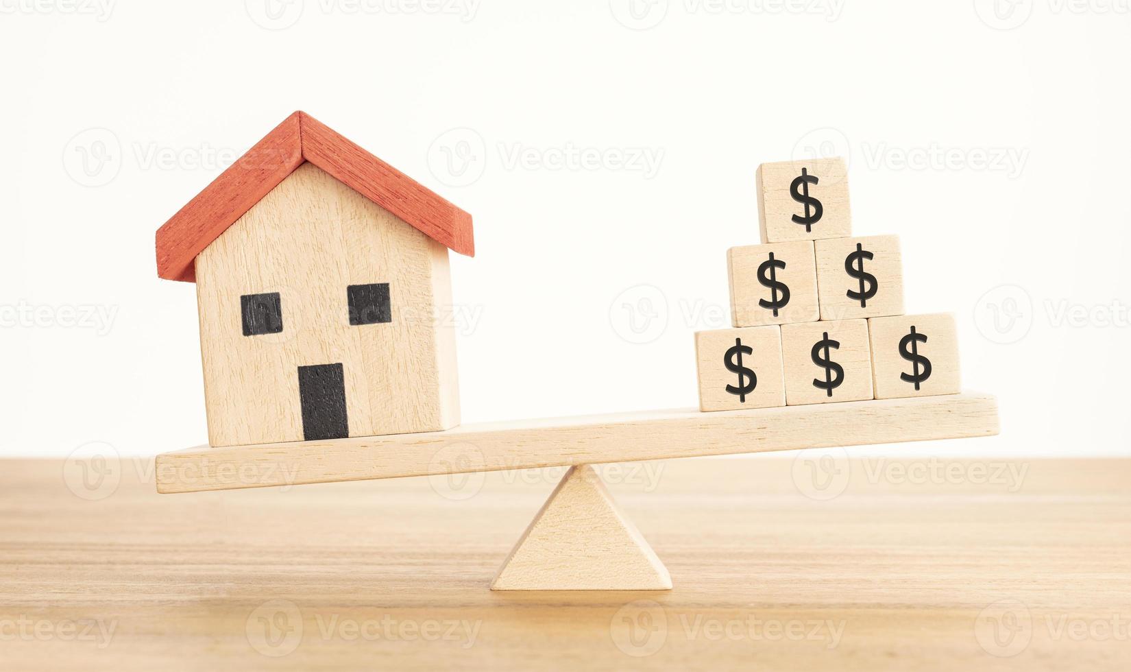 haus- oder immobilieninvestitionskonzept. Hausmodell und Holzklötze mit Dollarzeichen balancieren auf einer Wippe foto